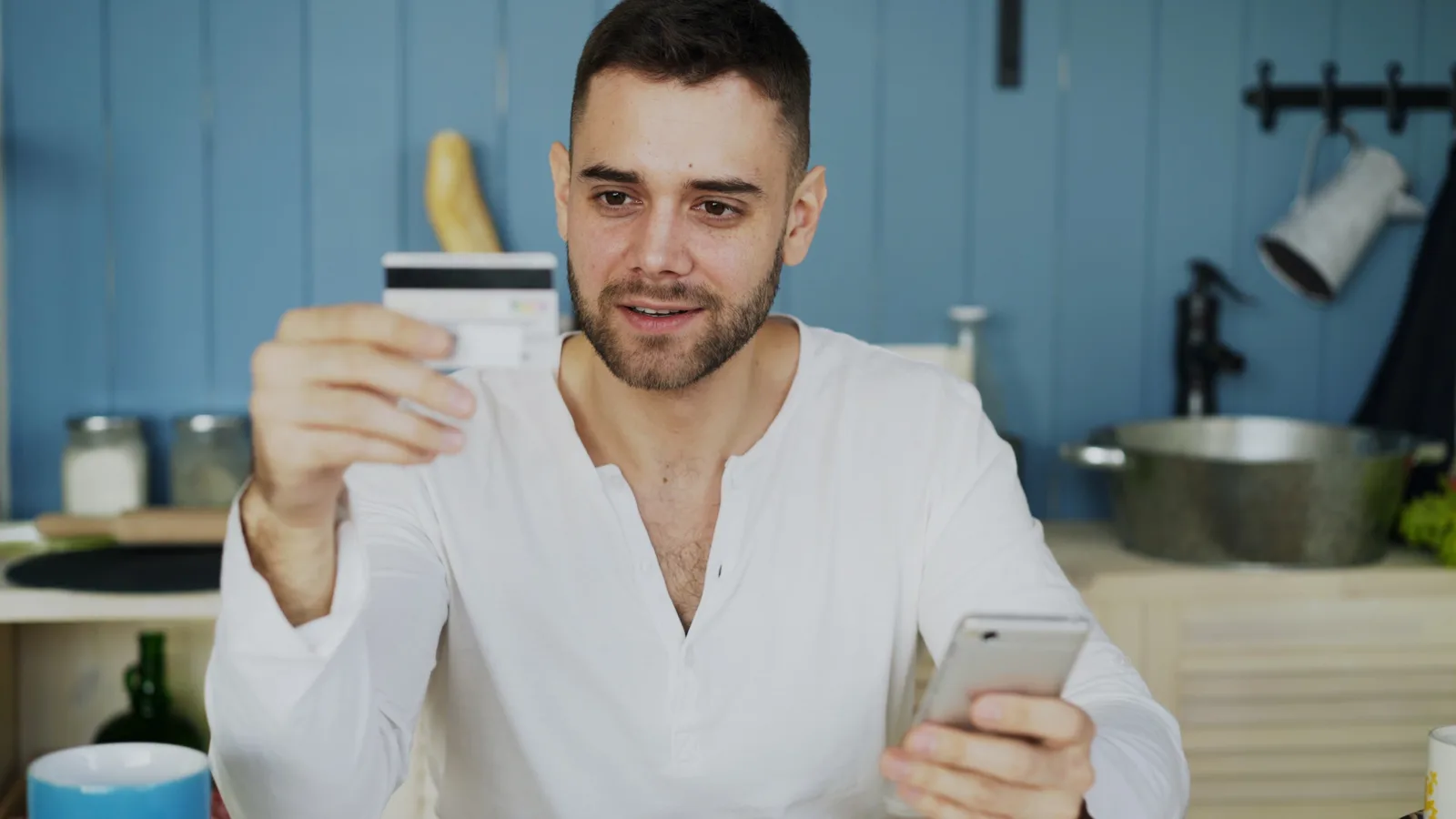 Man holding credit card and smartphone, shopping online at home.